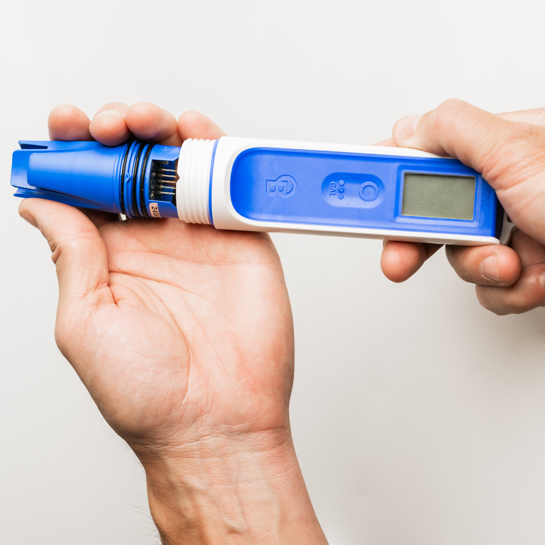 Hand holding a digital pH meter against a white background
