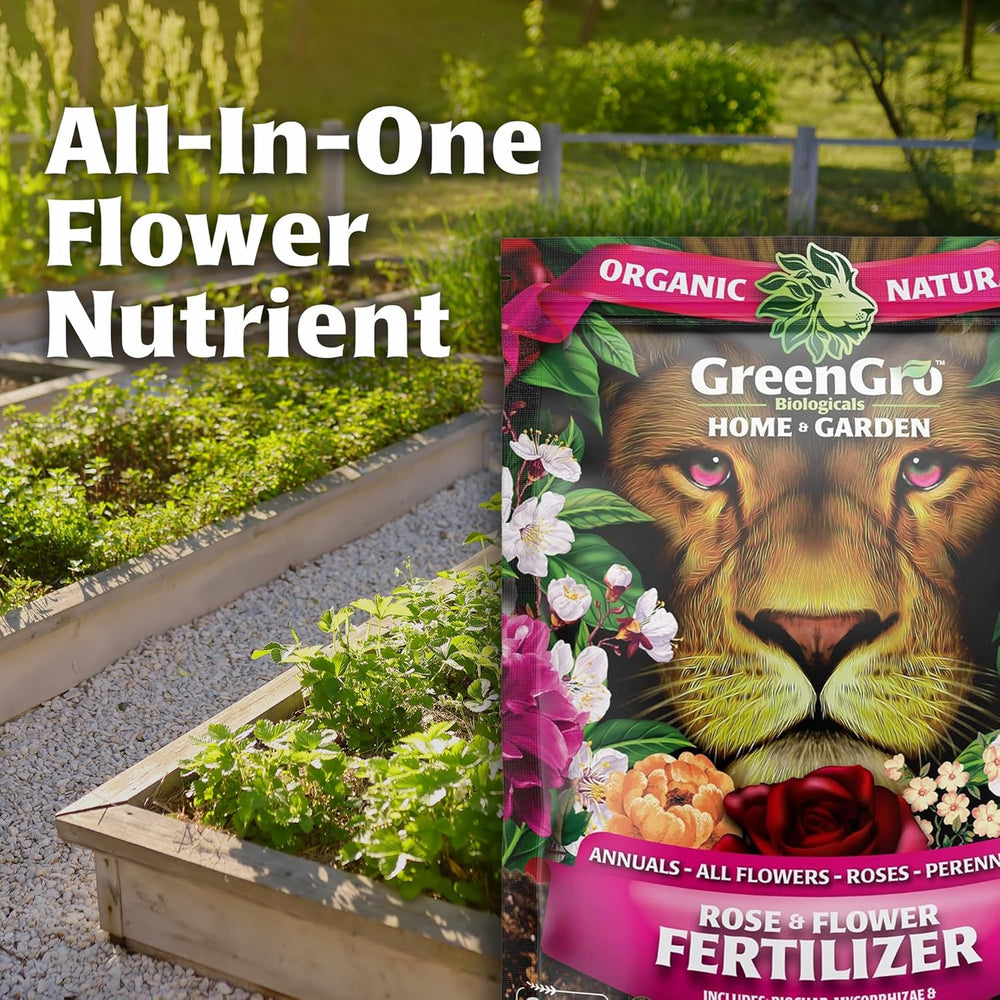A bag of GreenGro All-In-One Flower Nutrient fertilizer is shown in front of a garden bed with plants and a fence. The bag features a lion face illustration and pink floral accents, with text reading 'All-In-One Flower Nutrient' and 'Rose & Flower Fertilizer'.
