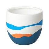 White ceramic cup with blue and orange design on a beige surface