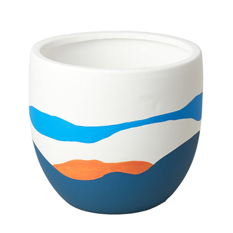White ceramic cup with blue and orange design on a beige surface