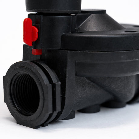 Close-up of a black mechanical component with a red valve on a white background