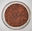 Close-up of ground coffee in a glass bowl on a light gray background