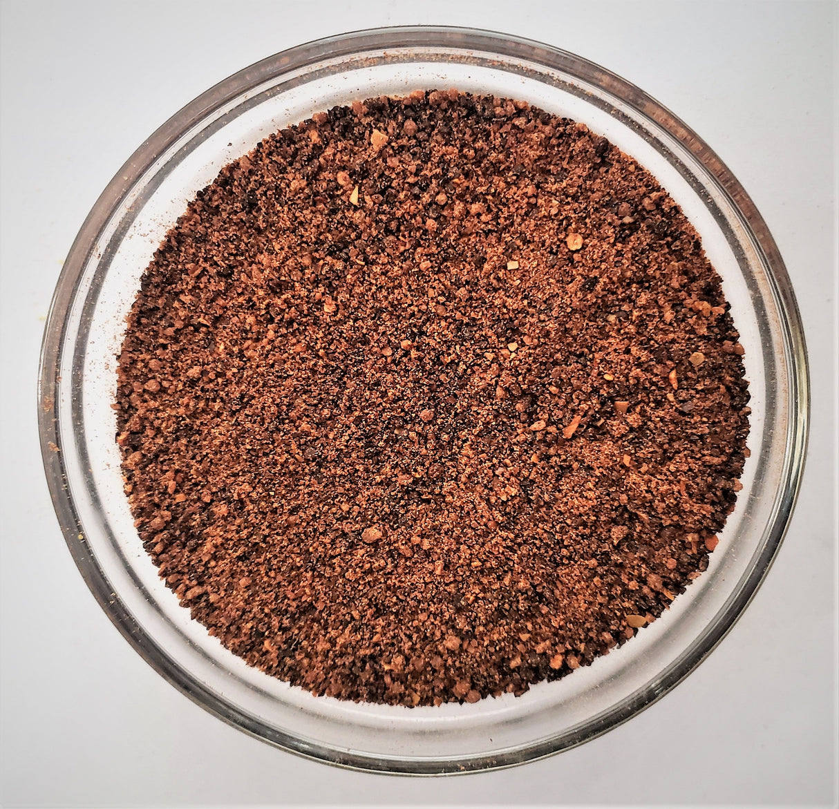 Close-up of ground coffee in a glass bowl on a light gray background