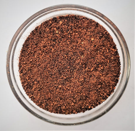 Close-up of ground coffee in a glass bowl on a light gray background