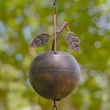 Decorative metal wind chime with hanging leaves against a blurred natural background