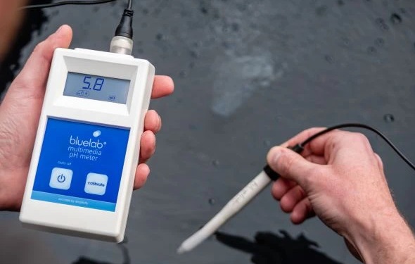 hands holding Bluelab Multimedia pH Meter testing water