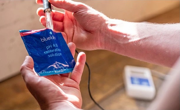 hands holding bluelab probe in ph calibration packet